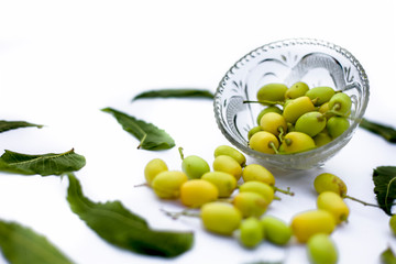 Neem fruit or nim fruit or Indian lilac fruit in a glass bowl isolated on white along with some fresh leaves also.