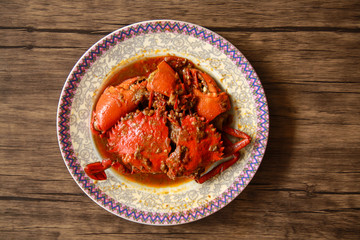 Crab in Padang sauce or Padang crab (Indonesian: Kepiting saus Padang) on wood background.