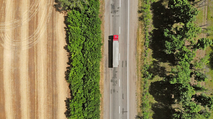 Aerial. Red truck on a road between fields. Transport logistics background.
