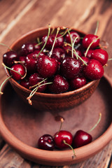 ripe sweet cherry in an earthenware dish on a wooden background