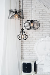 Black lamps in light bedroom interior. Three modern black lamps hanging