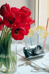 red flowers, retro camera and lemonade on a white background