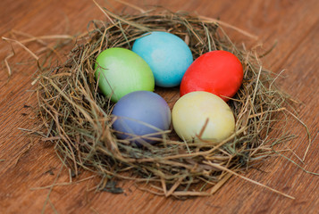 Easter eggs in a basket decorated with straw on a wooden rustic background 