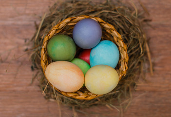 Easter eggs in a basket decorated with straw on a wooden rustic background 