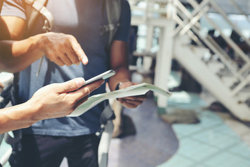 Obraz premium Two young travelers are planning a tour by looking at the map and searching on the smartphone.