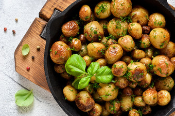 Fried, young potatoes with basil in a pan. View from above.