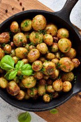 Fried, young potatoes with basil in a pan. View from above.