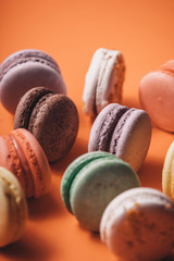 Traditional delicious french set of macaron on coral or orange background. Sweet dessert.