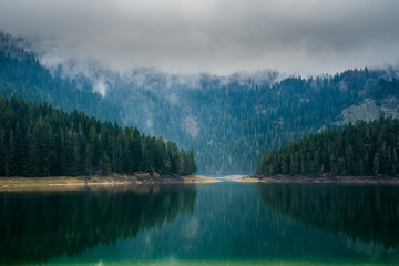 Montenegro, Calm waters of black lake nature paradise in durmitor national park landscape in foggy mood in the evening