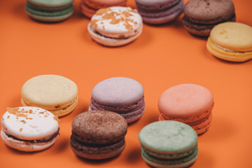 Fototapeta na wymiar Traditional french dessert of colorful macaron set on coral or orange background. Delicious sweet food.