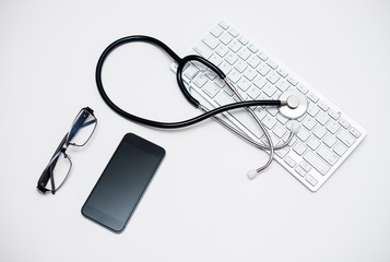 The concept of medicine. Stethoscope, keyboard, pills. Isolated on white background. smartphone black screen. pen notebook. spectacles