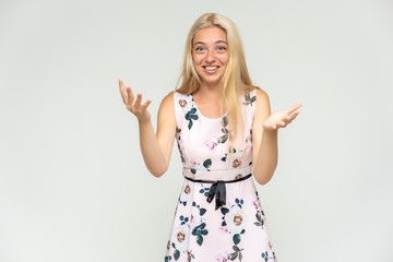 Portrait of a cute beautiful pretty woman girl with long beautiful hair on a white background in a pink dress with a pattern. Shows many different emotions, smiles and talks. Made in a studio.