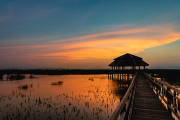 Fototapeta na wymiar Sunset with wooden bridge and pavilion in the lake with cloud and twilight sky at Khao Sam Roi Yot National Park, Thailand.