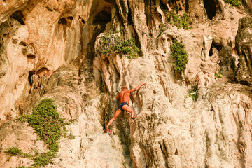 A senior man free solo climber hangs on the cliff of Rai Leh.