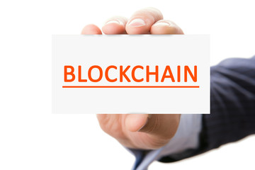 Male hand on a white background shows the viewer a card with the inscription Blockchain. Blockchain is a growing list of records, called blocks, that are linked using cryptography