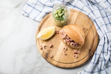Nordseekrabben Brötchen als Fischbrötchen mit Gurkensalat und Zitrone auf Holz Brett und Marmor Tisch