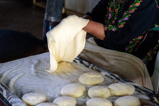 Close up Arabian old woman hand cooking flatbread or laffa or pita bread for Ramadan Arabic holiday.