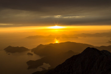 Mountains and the sea, sunset, sky in pastel colors, light haze, blur.
