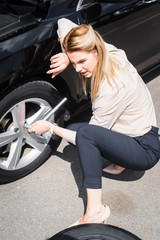 Fototapeta na wymiar tired businesswoman with tool in hand sitting near broken auto, car insurance concept