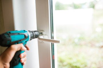 Close-up, hand with a screwdriver tightens the fixing screw of the window stopper. work with a drill. home repair