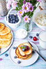Cottage cheese pancakes (syrniki). Homemade cheesecakes from cottage cheese with sour cream, berries and milk. Traditional Russian dish. Close-up.
