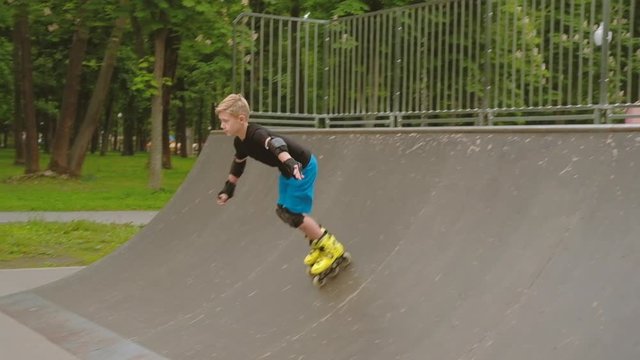 Kids extreme leisure. Rollerblader skating down the ramp in a park