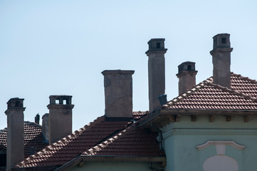 House roofs and chimneys on clear blue sky background