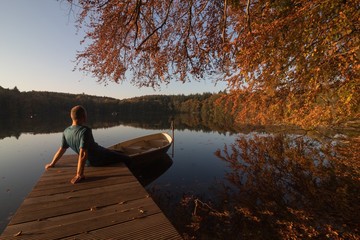 Fototapeta na wymiar man relaxing at a lake in beautiful fall landscape