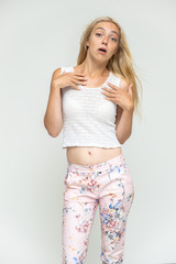 Obraz premium Portrait of a cute beautiful pretty woman girl with long beautiful hair on a white background in pink pants with a pattern. Shows many different emotions, smiles and talks. Made in a studio.