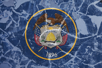 The national flag of the US state Utah in against a gray wall with cracks and faults on the day of independence in colors of blue and yellow. Political and religious disputes, customs and delivery.