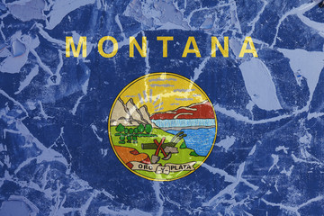 The national flag of the US state Montana in against a gray wall with cracks and faults on the day of independence in colors of blue and yellow. Political and religious disputes, customs and delivery.