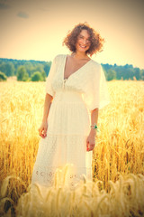 beautiful woman in white dress in a field outdoors on a summer day