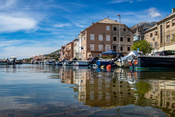 Reflection of houses in blue sea in little fishing port in town Karlobag in Croatia with Velebit mountain in background