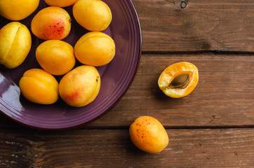Delicious ripe apricots in a wooden bowl on the table close-up.