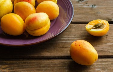 Delicious ripe apricots in a wooden bowl on the table close-up.