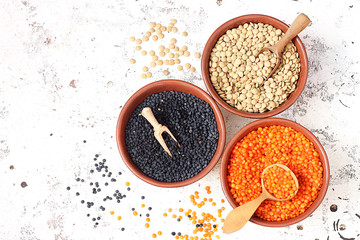 Bowls with different types of lentils on a white background
