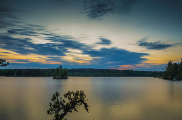 Peaceful movement of blue cloud on a countryside lake during the sunset through the orange horizon in beatiful day