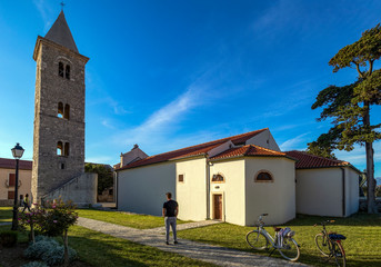 Man with bicycle near Church of St Anselm, Parish Church in town of Nin, Croatia