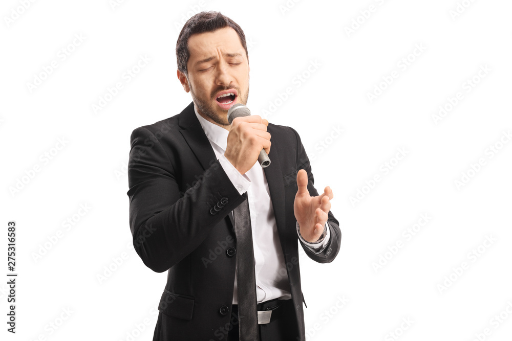 Wall mural Emotional young male singer singing on a microphone with  closed eyes