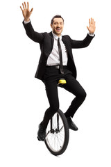 Young businessman in a suit riding a unicycle and waving with both hands © Ljupco Smokovski