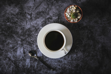 Black coffee in a white coffee cup and cactus placed on a black background