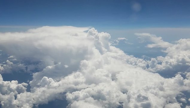 Aerial background with a real time flight above puffy clouds, as seen from an airplane.