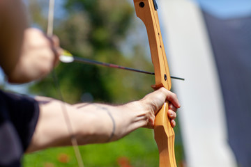 Archer holding wooden bow and aiming at target