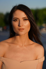 Fototapeta na wymiar Facial portrait of a beautiful dark-haired gypsy model in a beige dress at summer day.