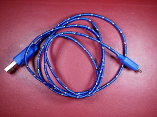 USB cable in blue braid with white dots on red background.