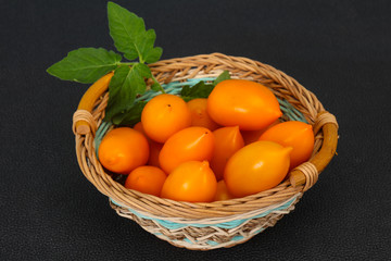 Yellow tomato heap in the wooden bowl