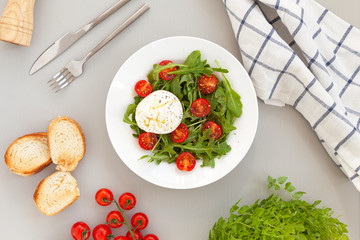 Burrata cheese. Salad of fresh arugula, cherry tomatoes and soft Italian cheese burrata with olive oil. Italian food. 
