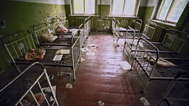 Top fisheye view of a frightening abandoned nursery school in Prypiat. Left dirty shabby beds and toys in a dermitory. High radioactivity zone. Chernobyl, Ukraine.