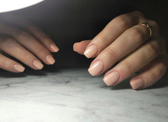 Gently pink manicure young girl on a dark background