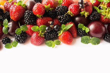 Mix berries and fruits on white background. Ripe blackberries, strawberries, blackcurrants and plums. Top view. Background berries and fruits. Various fresh summer fruits.